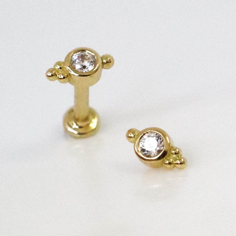 Ear piercing with set zircon and three small yellow gold balls