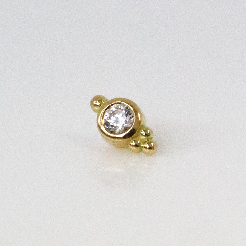 Ear piercing with set zircon and three small yellow gold balls