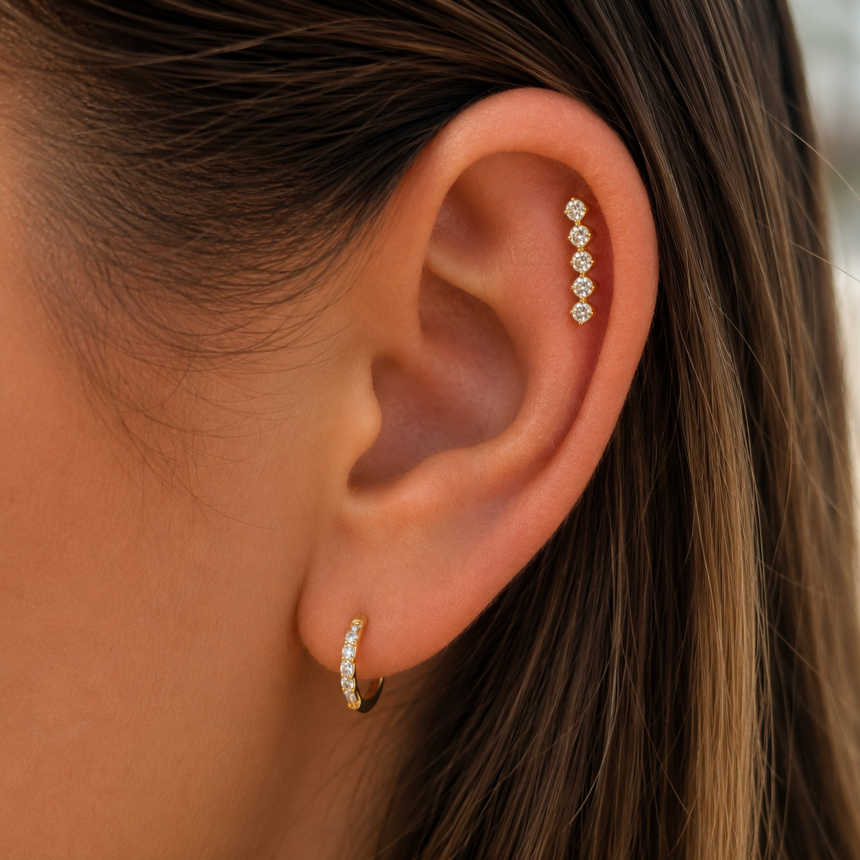 Piercing oreille en or jaune avec barrette de 5 zircons porté sur une oreille