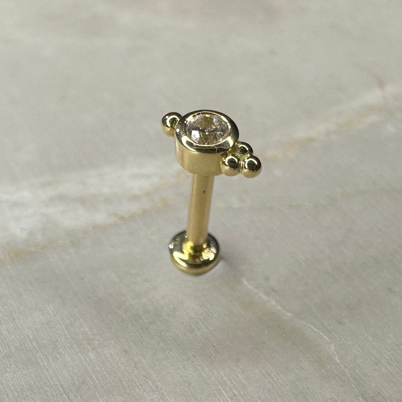 Ear piercing with set zircon and three small yellow gold balls