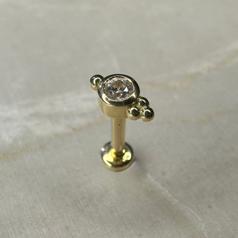Ear piercing with set zircon and three small yellow gold balls