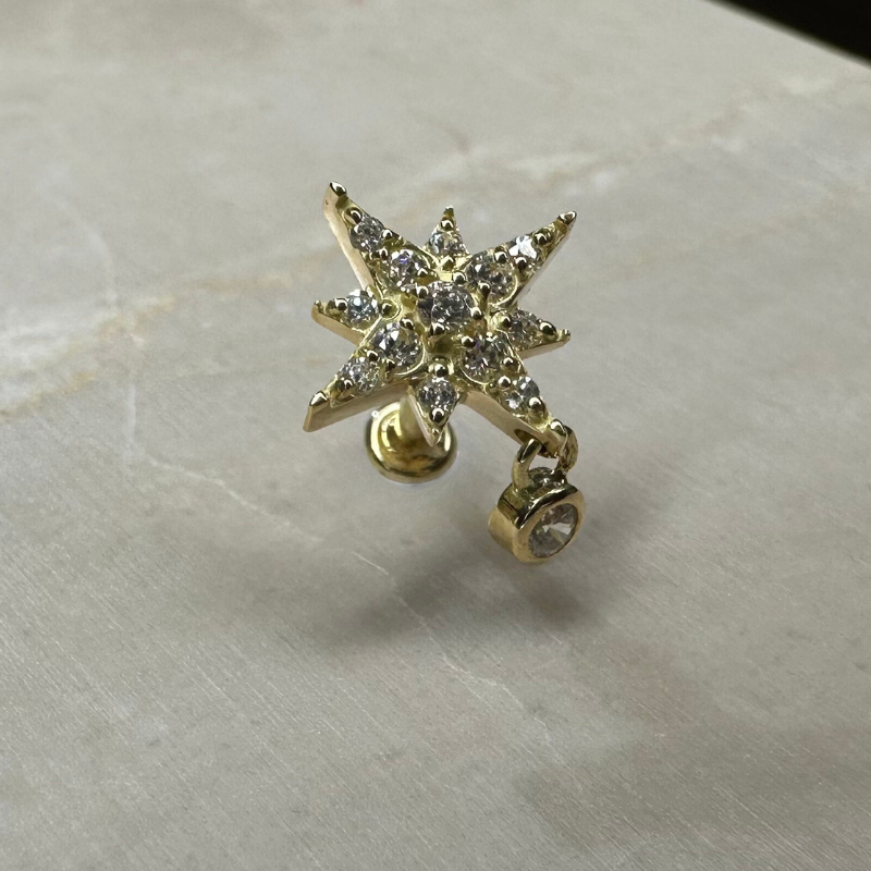 Star piercing with shiny pendant in yellow gold
