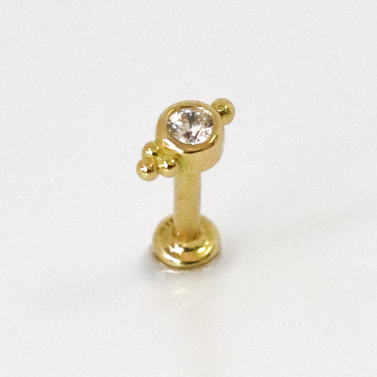 Piercing d'oreille avec zircon serti et trois petites boules en or jaune