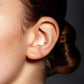 Yellow gold conch piercing with fuchsia zirconium oxide